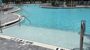Une piscine à l’eau claire, entourée de chaises longues et de parasols.