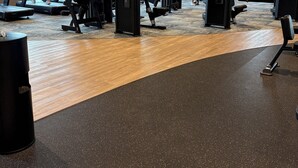 Une salle de sport équipée de tapis de course, d’appareils de musculation et dotée d’un plancher en bois.