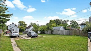 A residential backyard with a grassy lawn, two parked cars, and a wooden fence.