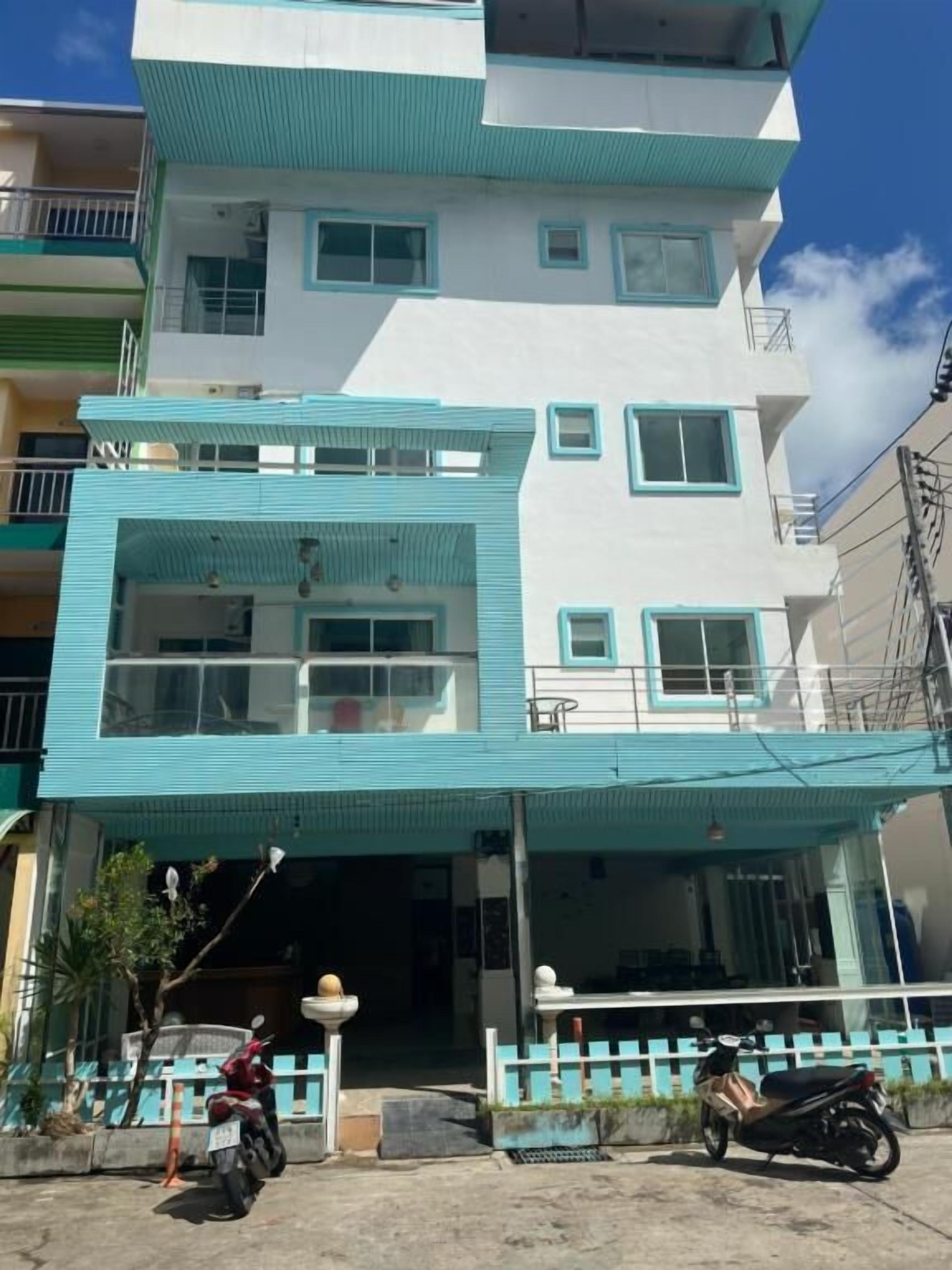 A multi-story building with a flat roof and a balcony on the second floor.