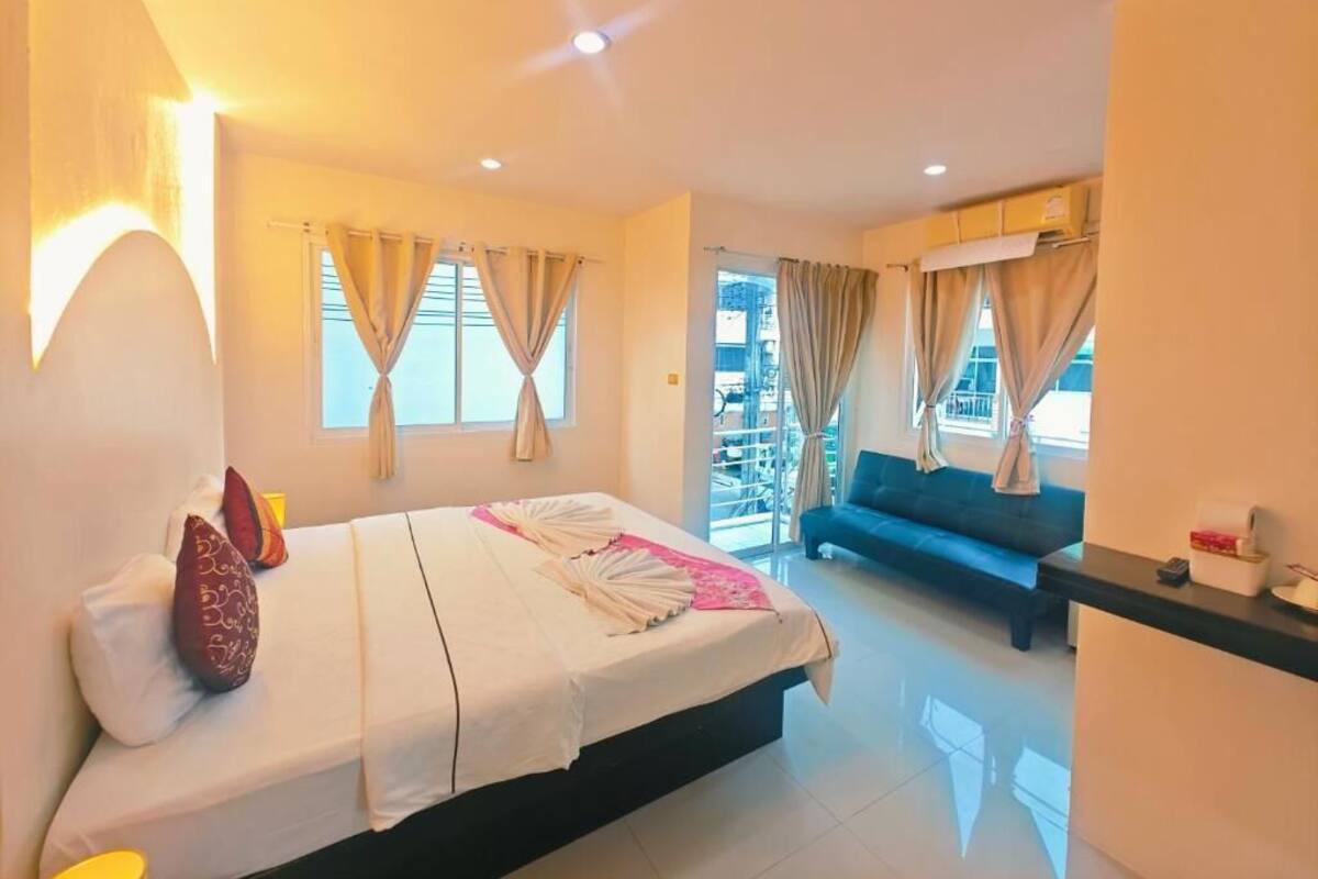 A hotel room with a bed, a sofa, and a small table.