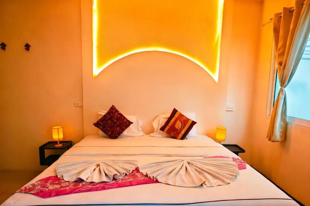 A hotel room with a bed, two bedside lamps, and a window with curtains.