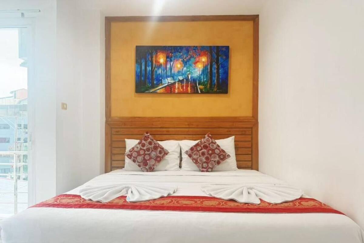 A hotel room with a large bed, a wooden headboard, and a painting above the bed.
