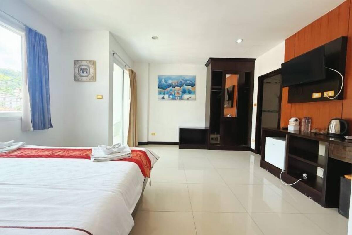 A hotel room with two beds, a TV, a desk, and a painting on the wall.