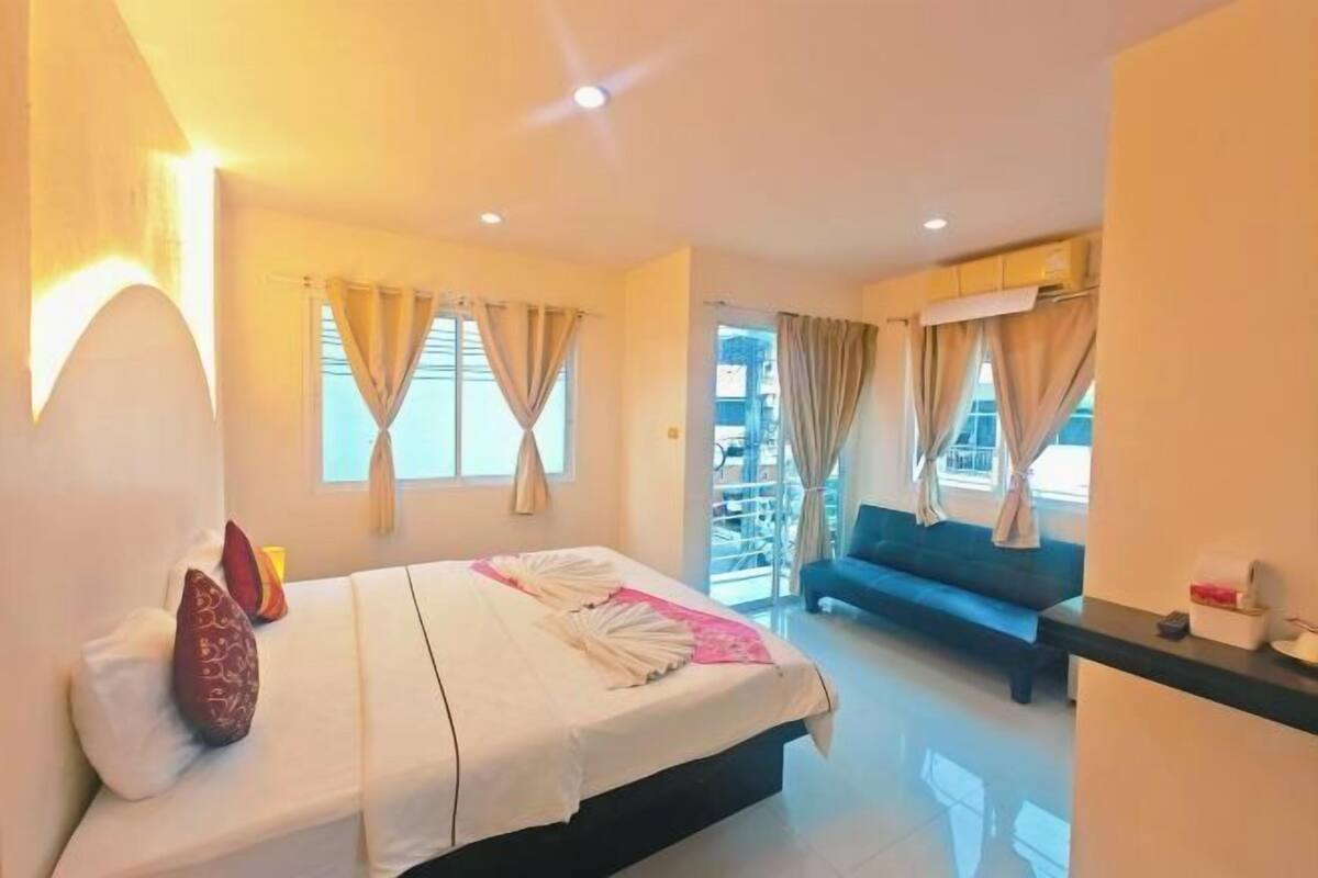 A hotel room with a bed, a sofa, and a balcony.