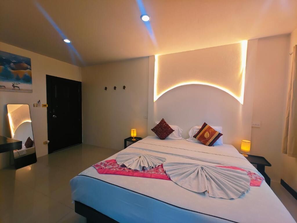 A hotel room with a large bed, two bedside tables with lamps, a door, and a wall-mounted artwork.