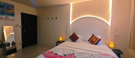 A hotel room with a large bed, two bedside tables with lamps, a door, and a wall-mounted artwork.