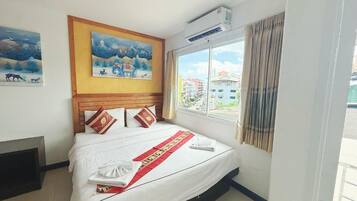 Hotelkamer met een bed, een raam met gordijnen, een wandairconditioner en twee ingelijste foto's.