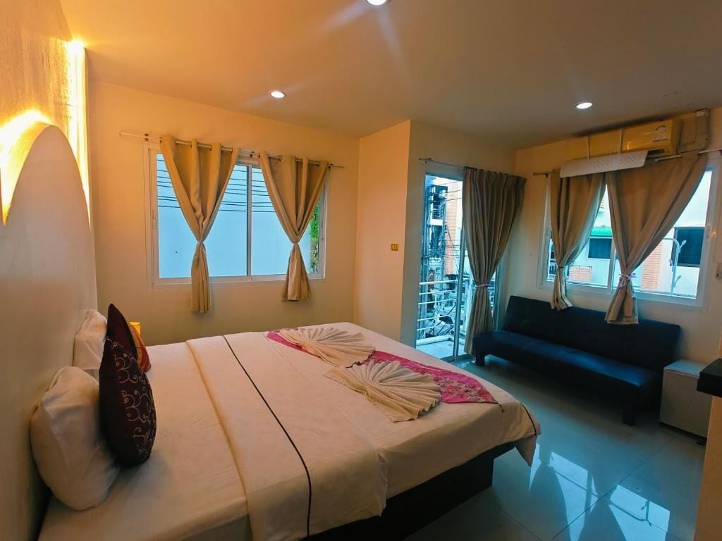 A hotel room with a bed, a sofa, a balcony, and curtains.