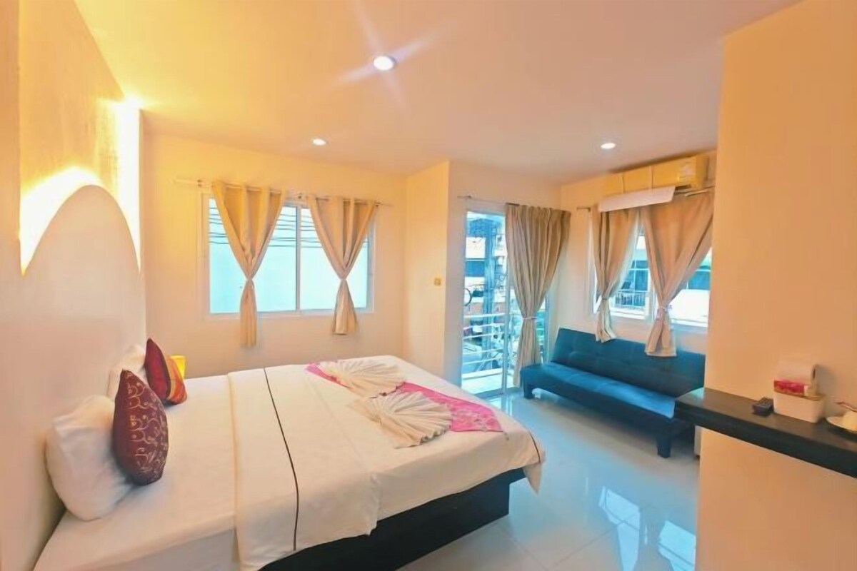 A hotel room with a bed, a sofa, and a balcony.