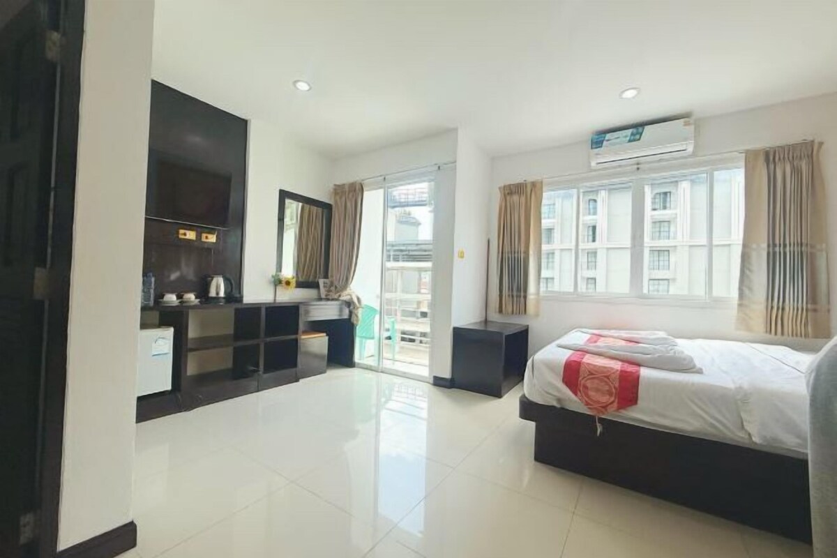 A modern hotel room with a bed, a TV, a desk, and a balcony.