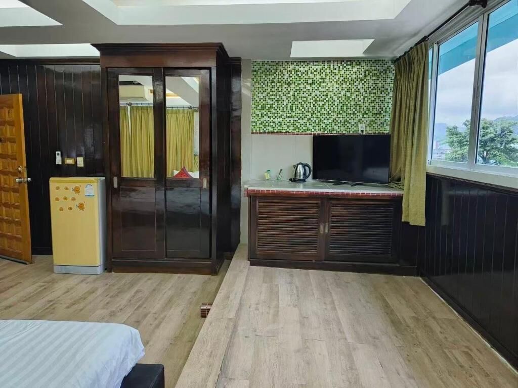 A hotel room with a bed, a small kitchenette, a TV, and a window with a view.