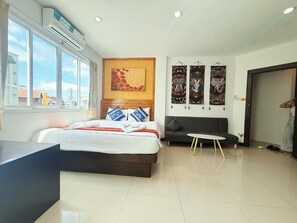 A modern hotel room with a large bed, a sofa, a small round table, and artwork on the walls. - Abby's House Hotel (Patong)