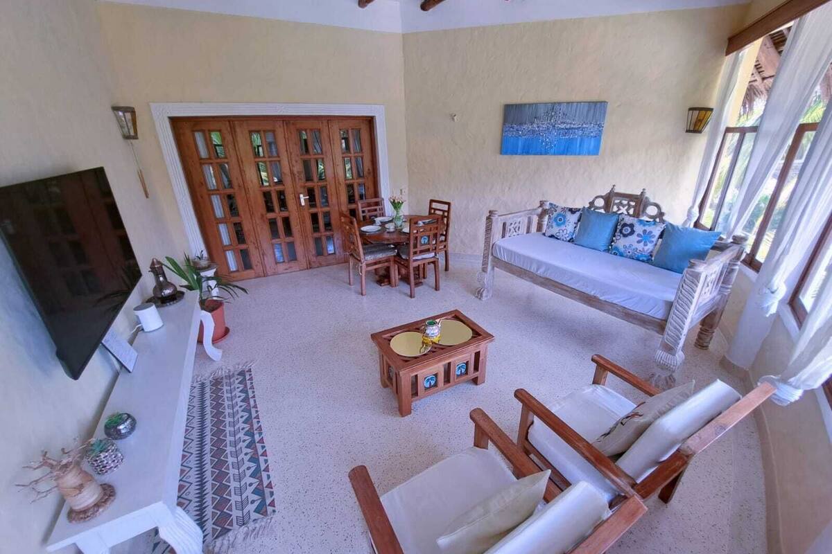 A spacious living area with a sofa, chairs, a coffee table, a TV, and a dining set.