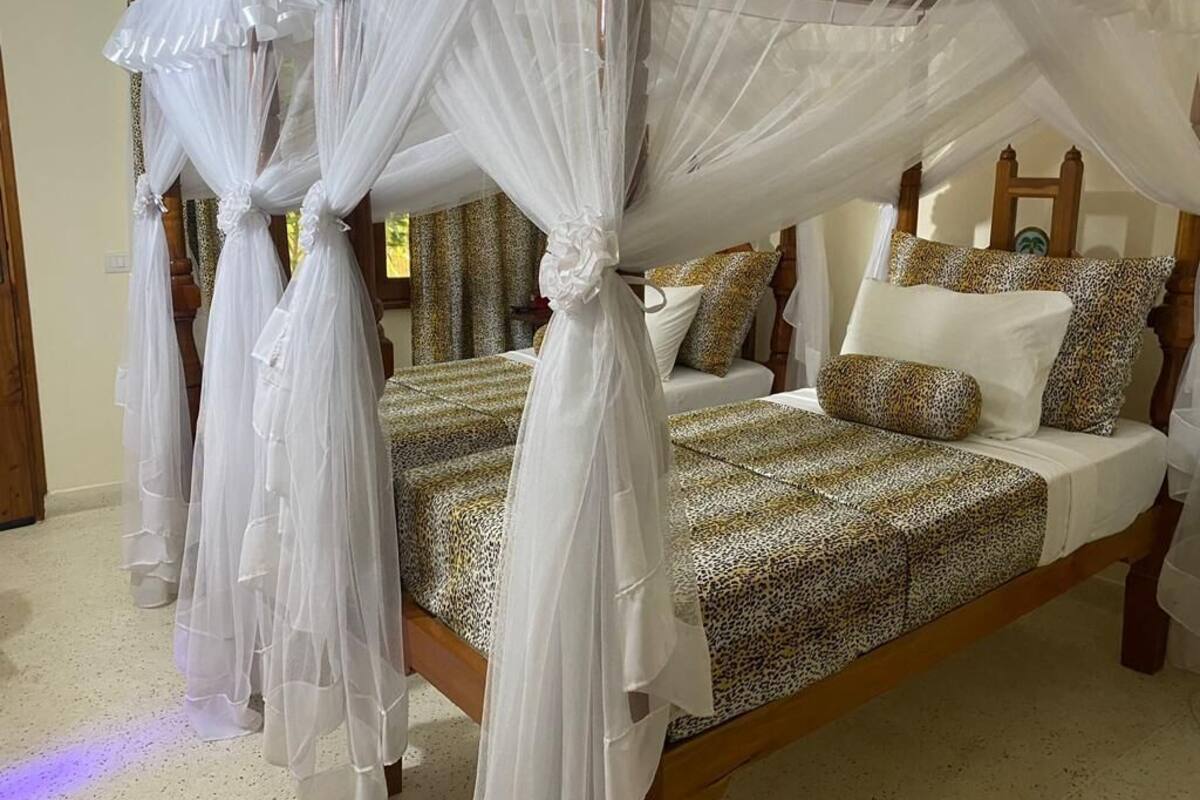 A four-poster canopy bed with a leopard print bedspread and white pillows.