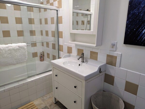 A bathroom with a bathtub, a sink, a mirror, and a shower. - Spacious 4-bed home with king suites, near Riverbanks Zoo and downtown Columbia. (West Columbia)