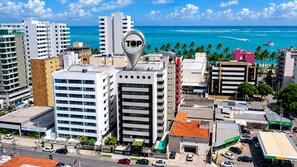 A cityscape with a prominent building marked 'TOP' and a view of the ocean. - Top Unique Maceió  (Maceió)