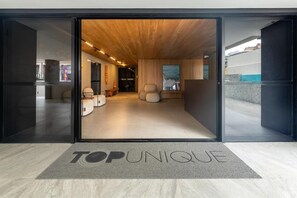 A modern interior with a wooden ceiling, a reception area with a sofa and chairs, and a 'TOP UNIQUE' sign on the floor. - Top Unique Maceió  (Maceió)