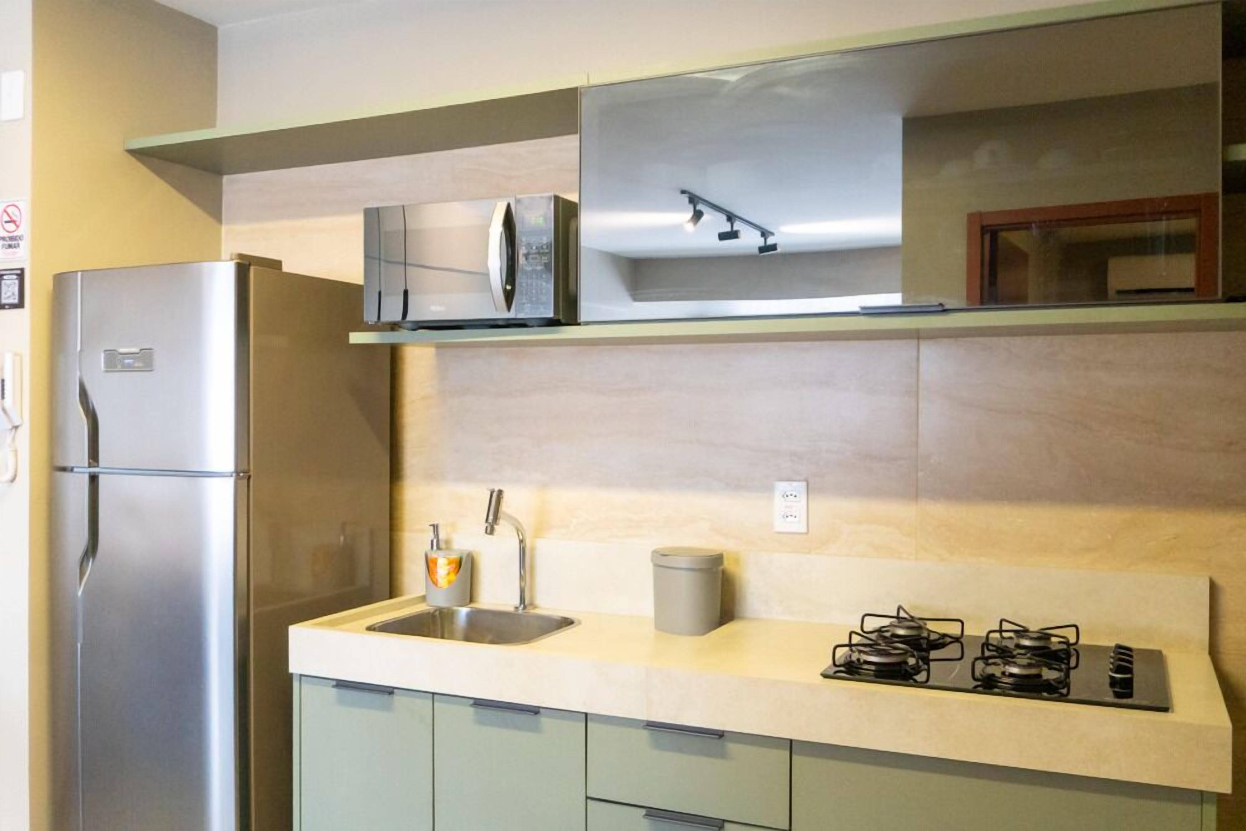 A kitchen with a stainless steel refrigerator, a microwave, a sink, and a gas stove.