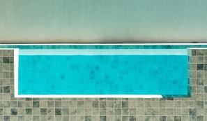 A swimming pool with a tiled border, surrounded by a tiled wall.