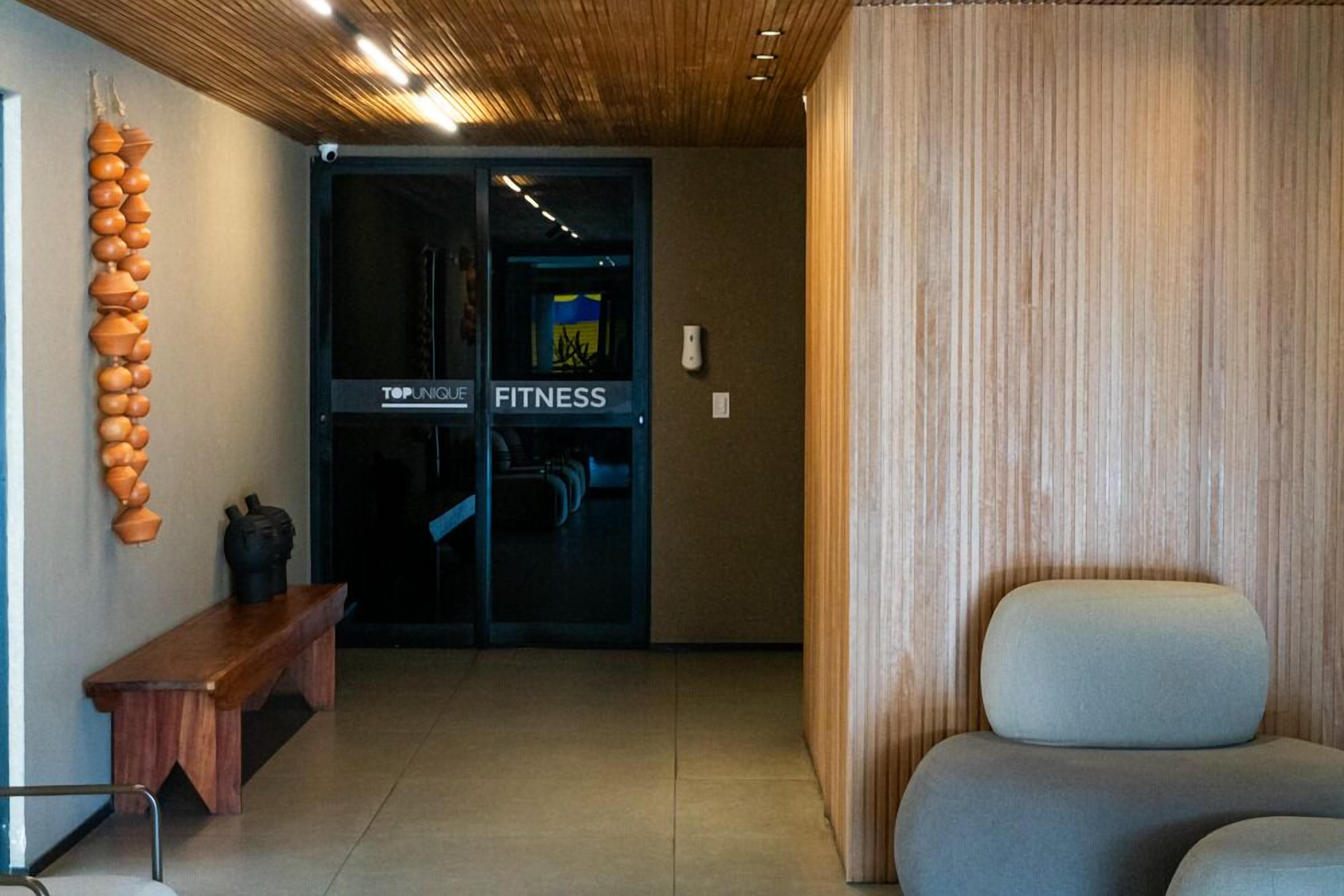 A modern interior with a bench, a wall-mounted sculpture, and a door labeled 'TOPUNIQUE FITNESS'.