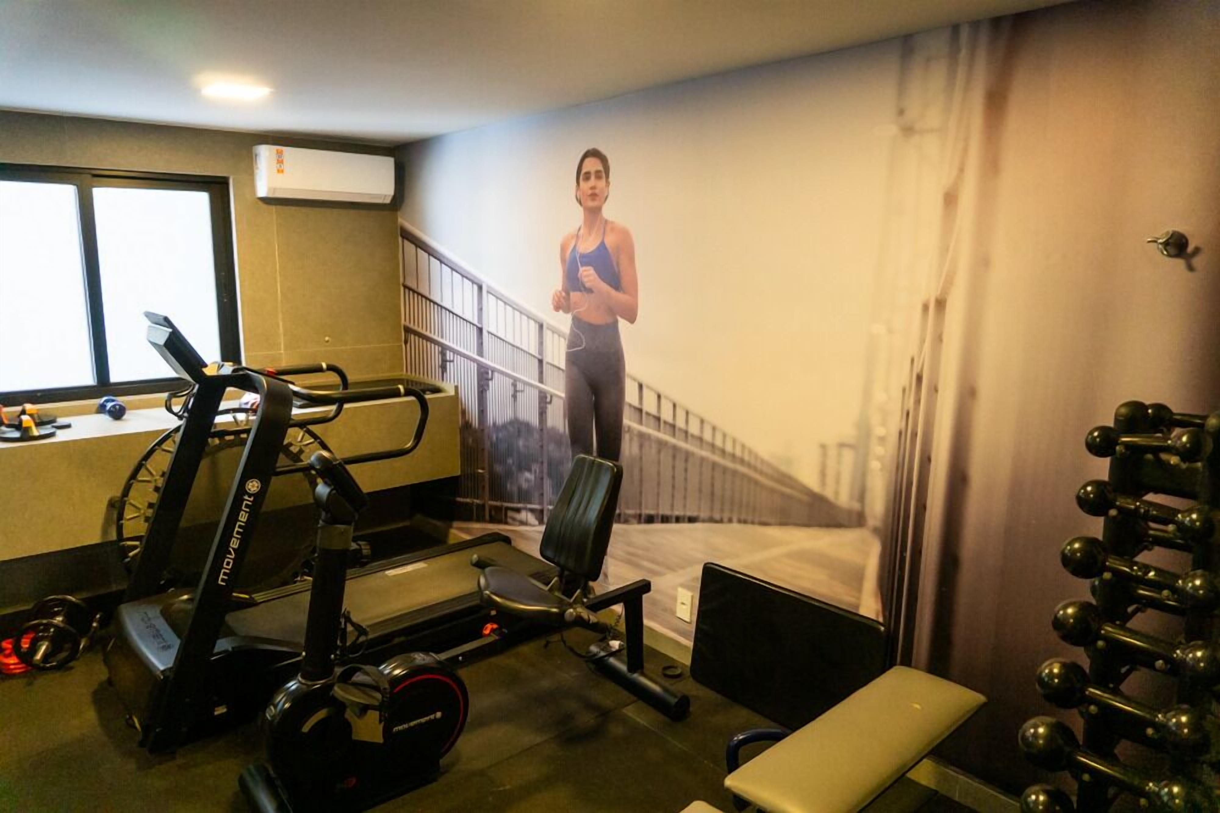 A gym with exercise equipment, a treadmill, a bench, and a wall with a person running.