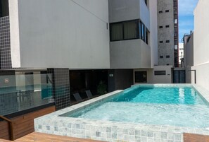 A modern building with a rooftop pool, a glass-enclosed area, and a tiled exterior. - Top Unique Maceió  (Maceió)