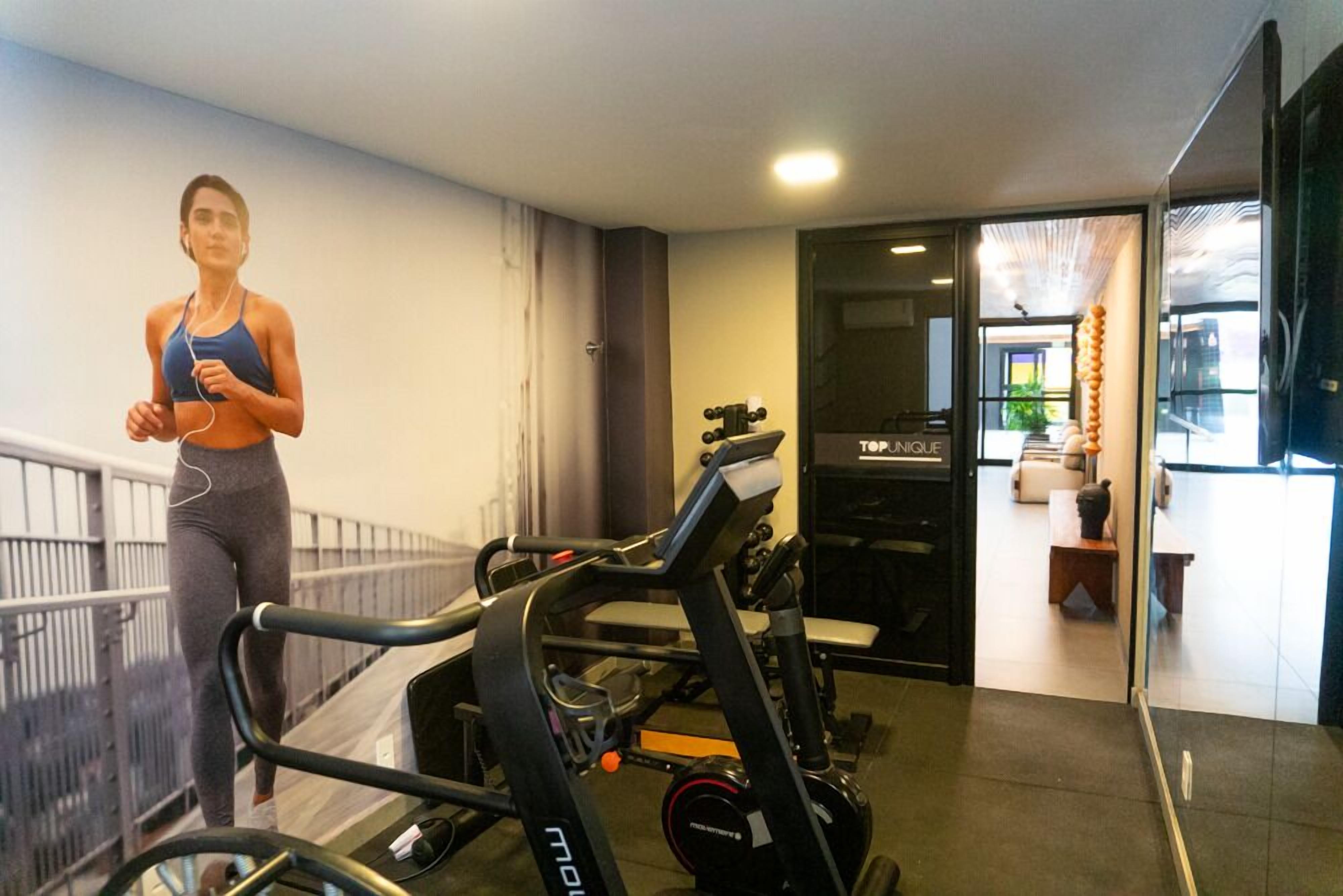 A gym with exercise equipment, a person jogging, and a view of a modern interior with a bench and a door labeled 'TOP NIGOL'.