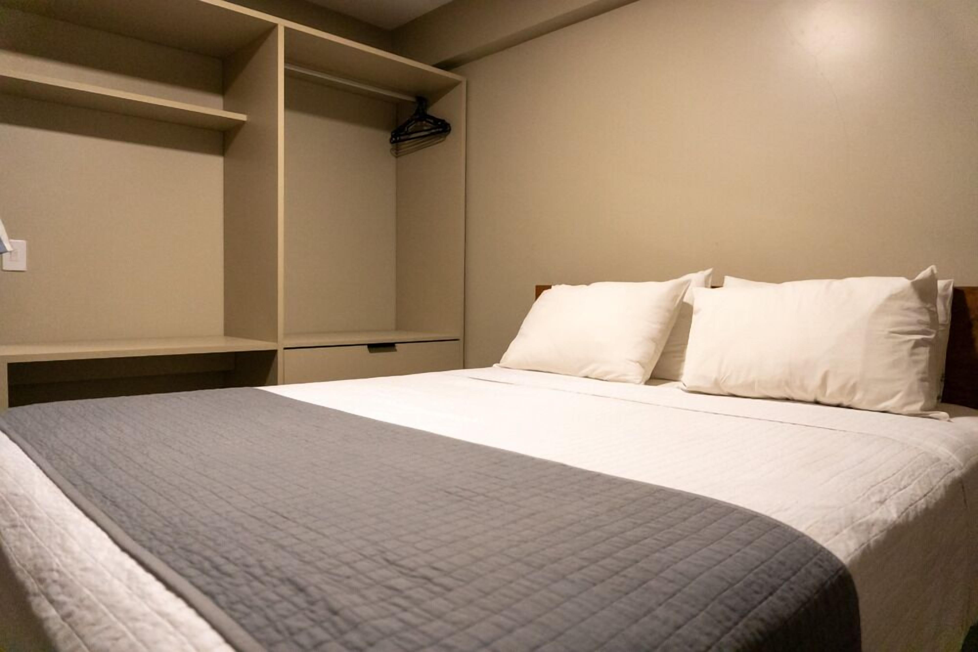 A hotel room with a bed, a wardrobe, and a hanging coat rack.