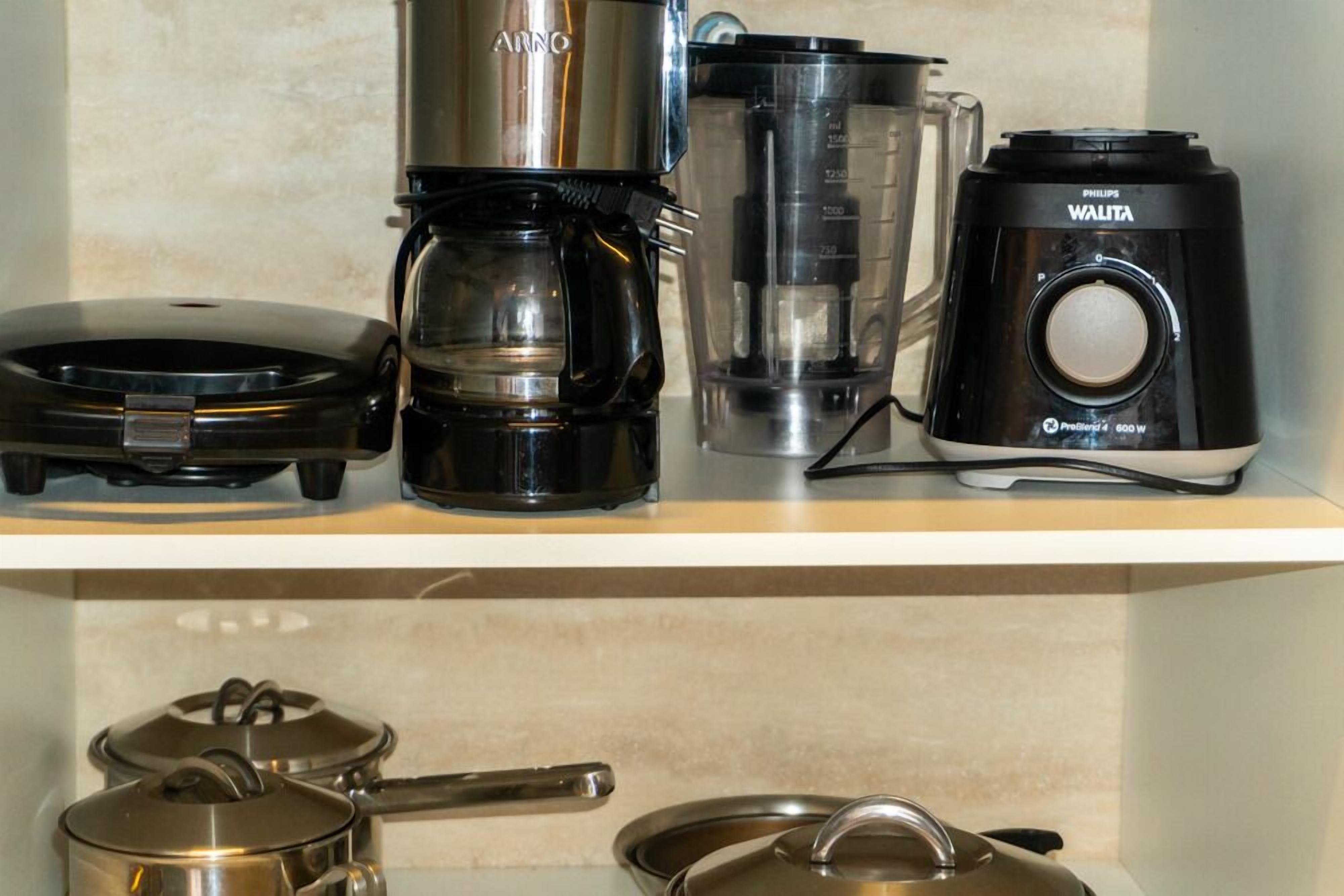 A kitchen with a coffee maker, blender, and pots.