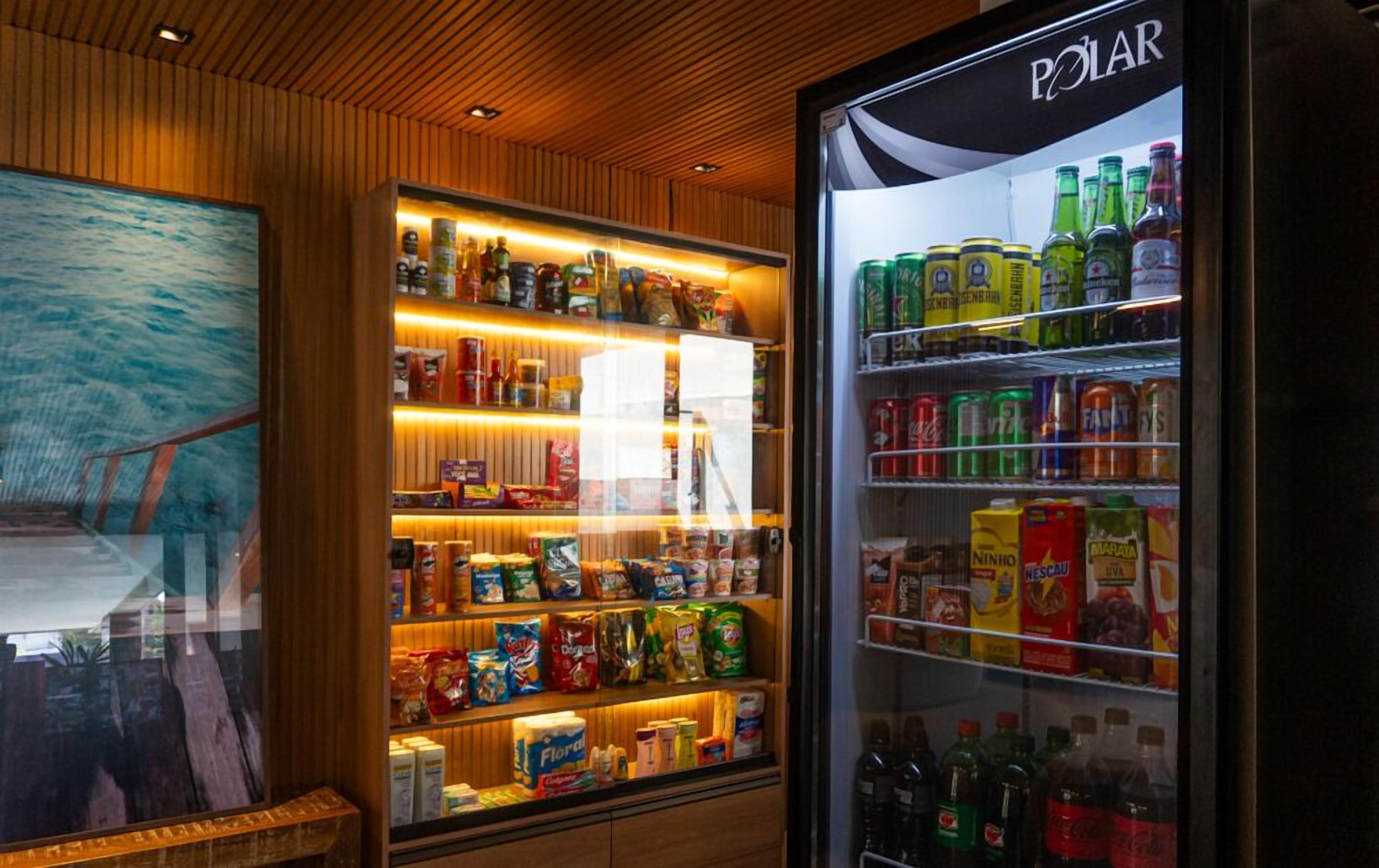 A refrigerated display case with various beverages and snacks, a wooden wall with a painting, and a ceiling with wooden panels.