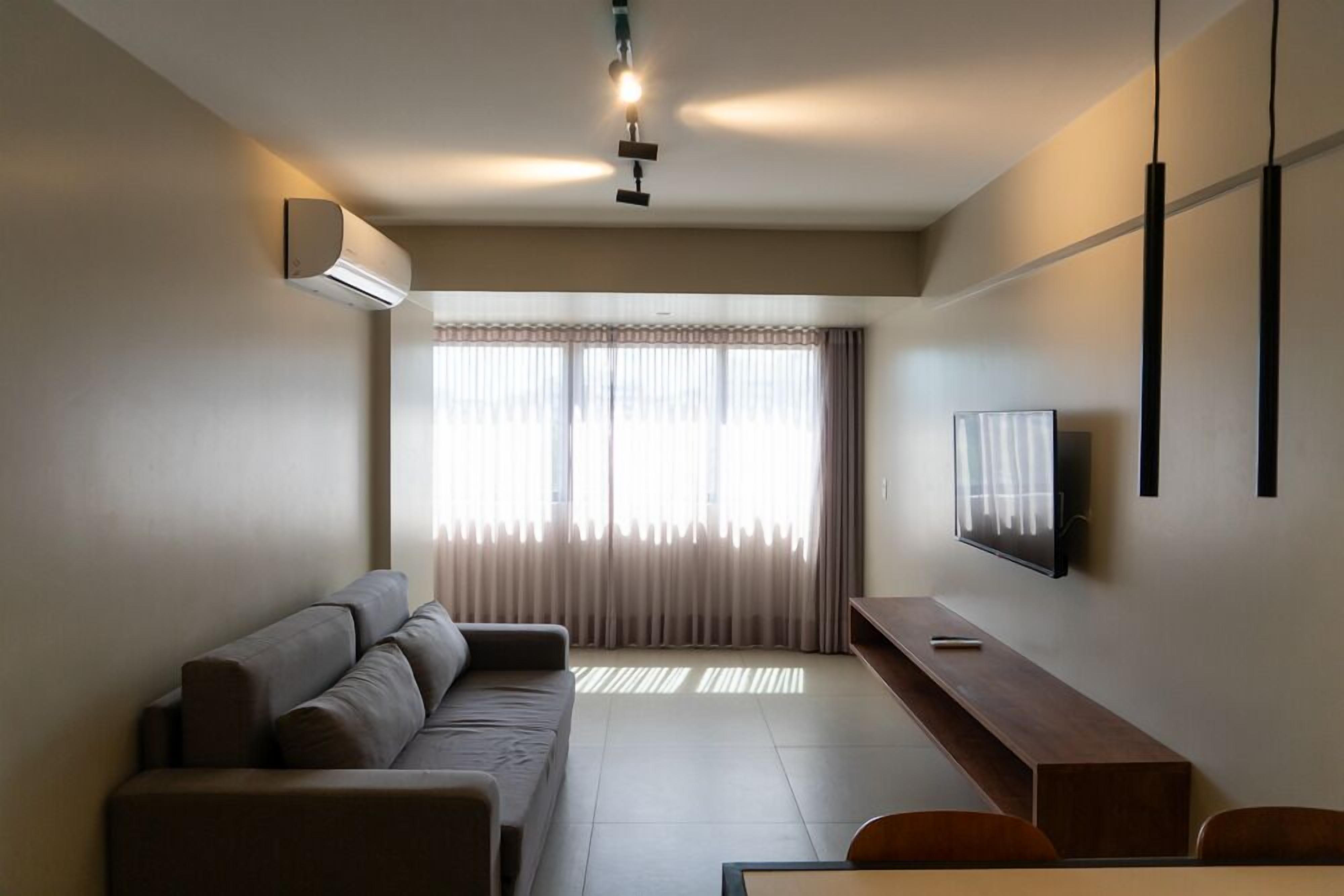 A modern living room with a sofa, a TV, and a dining area.