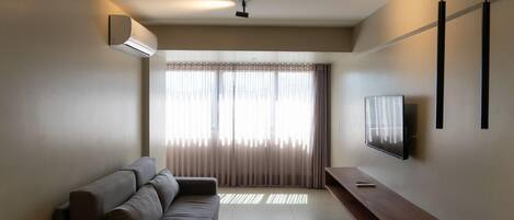 A modern living room with a sofa, a TV, and a dining area.