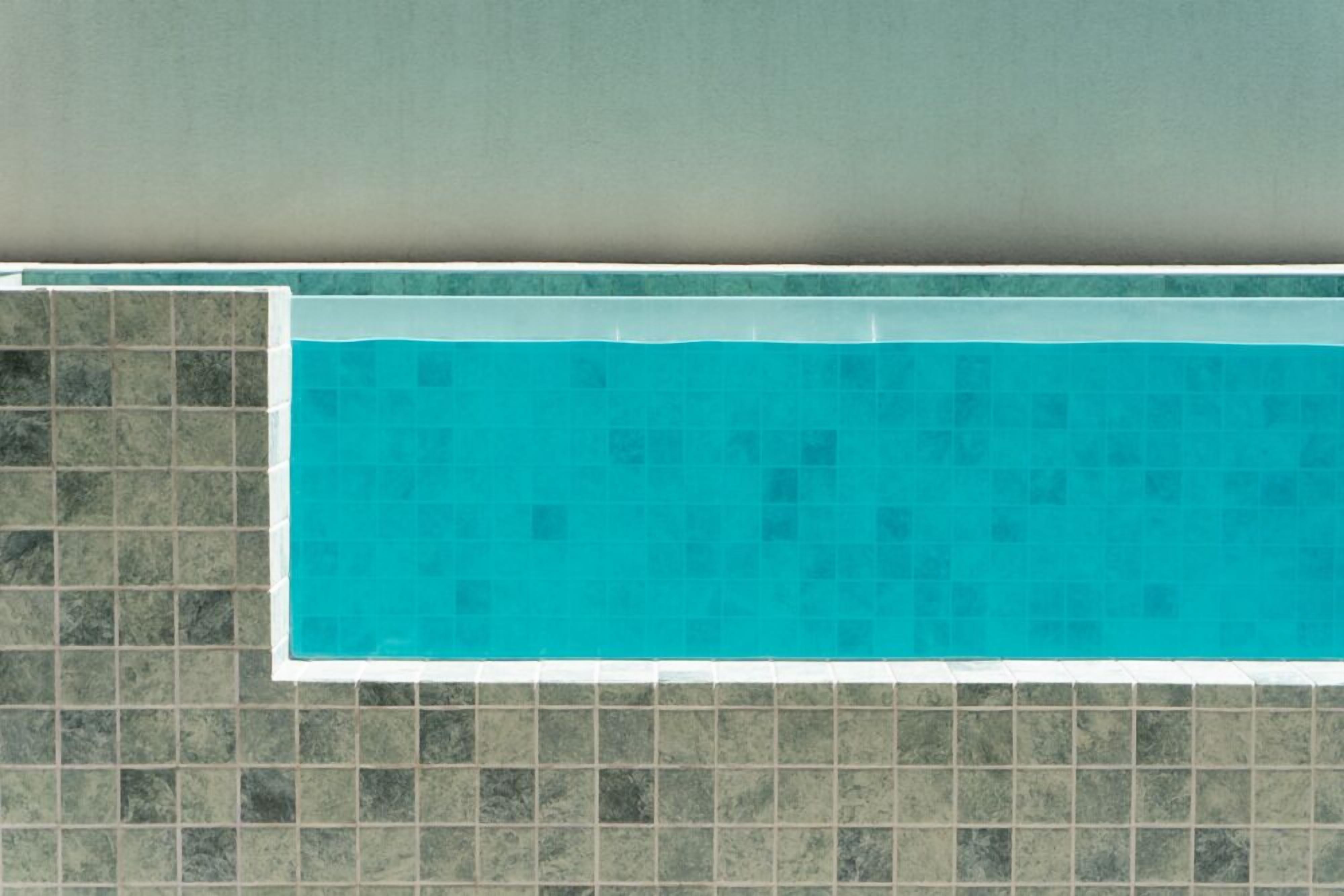 A swimming pool with a tiled border and a tiled wall.
