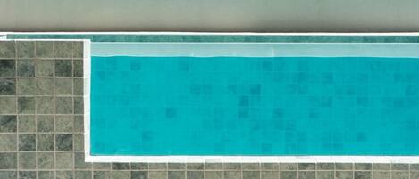 A swimming pool with a tiled border and a tiled wall.