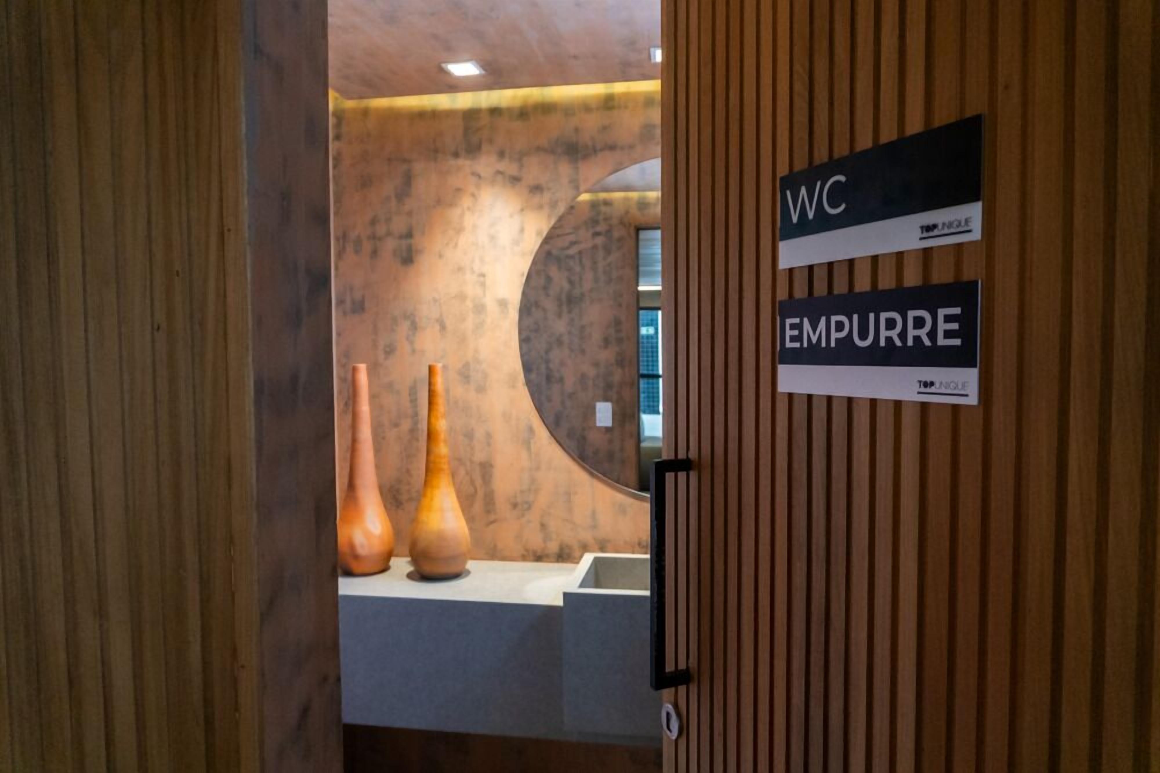 A wooden door with signs indicating 'WC' and 'EMPURRE.'