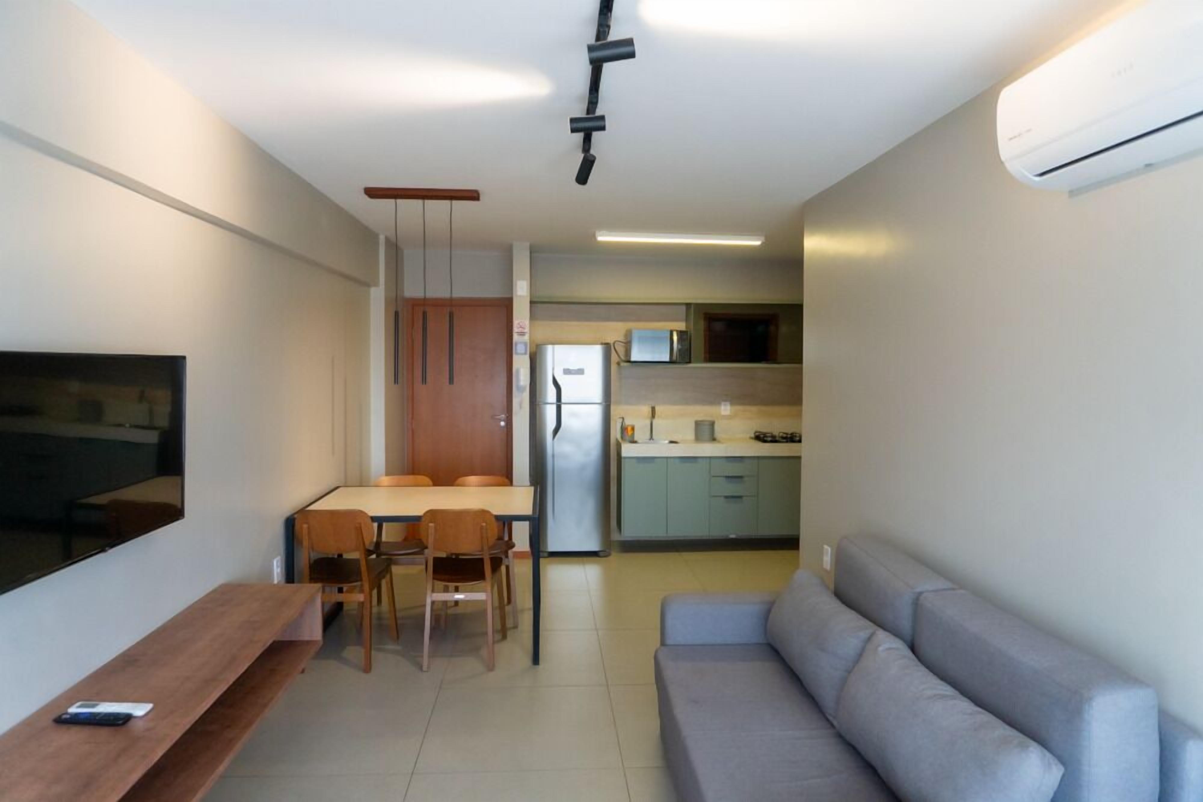 A compact living space with a sofa, a dining table with chairs, a TV, and a kitchenette.