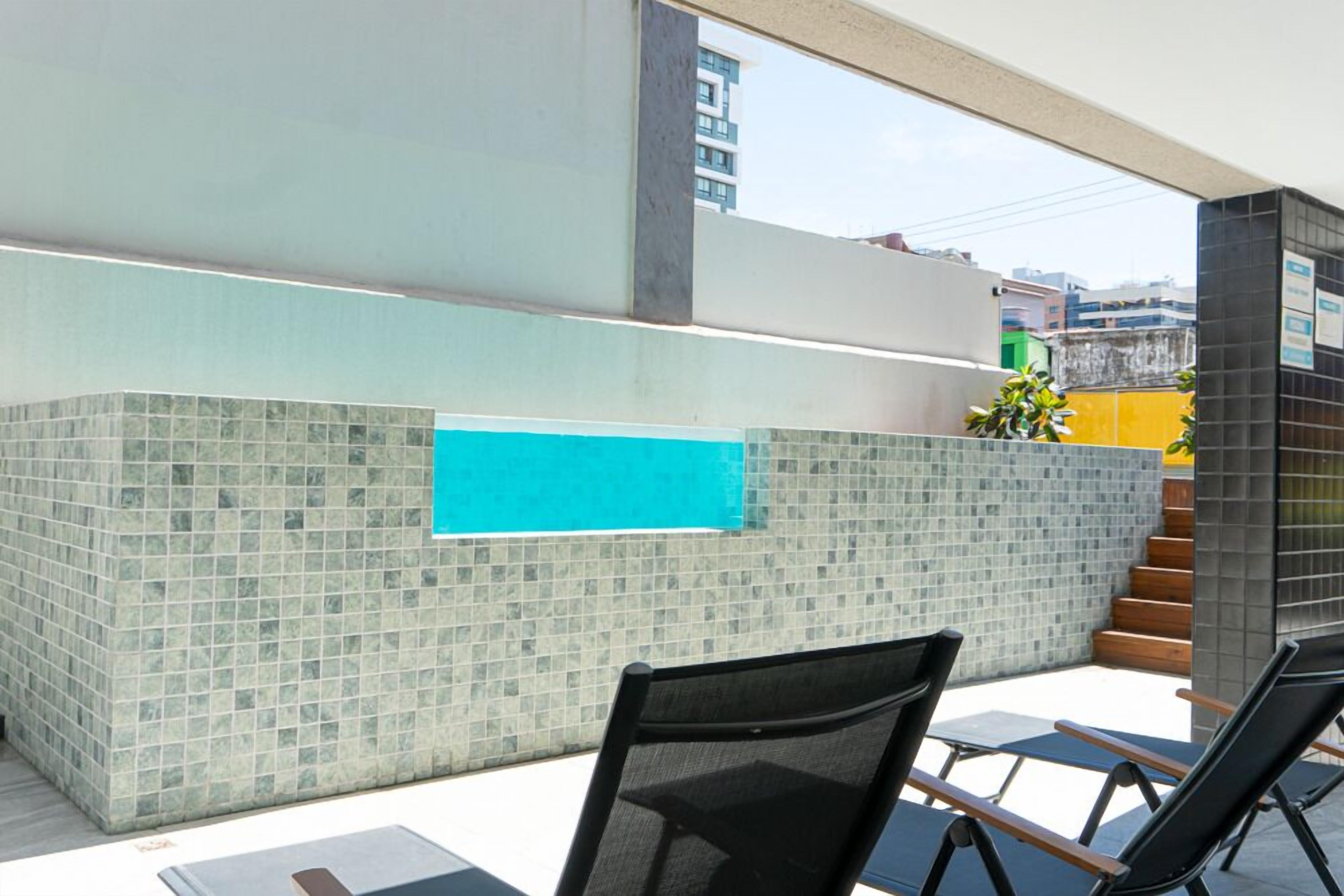 Un espace extérieur moderne doté d’une piscine, de murs carrelés et de coins salon.
