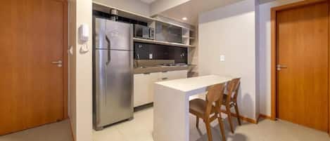 A compact kitchen with a refrigerator, microwave, and a small dining area with a table and chairs.