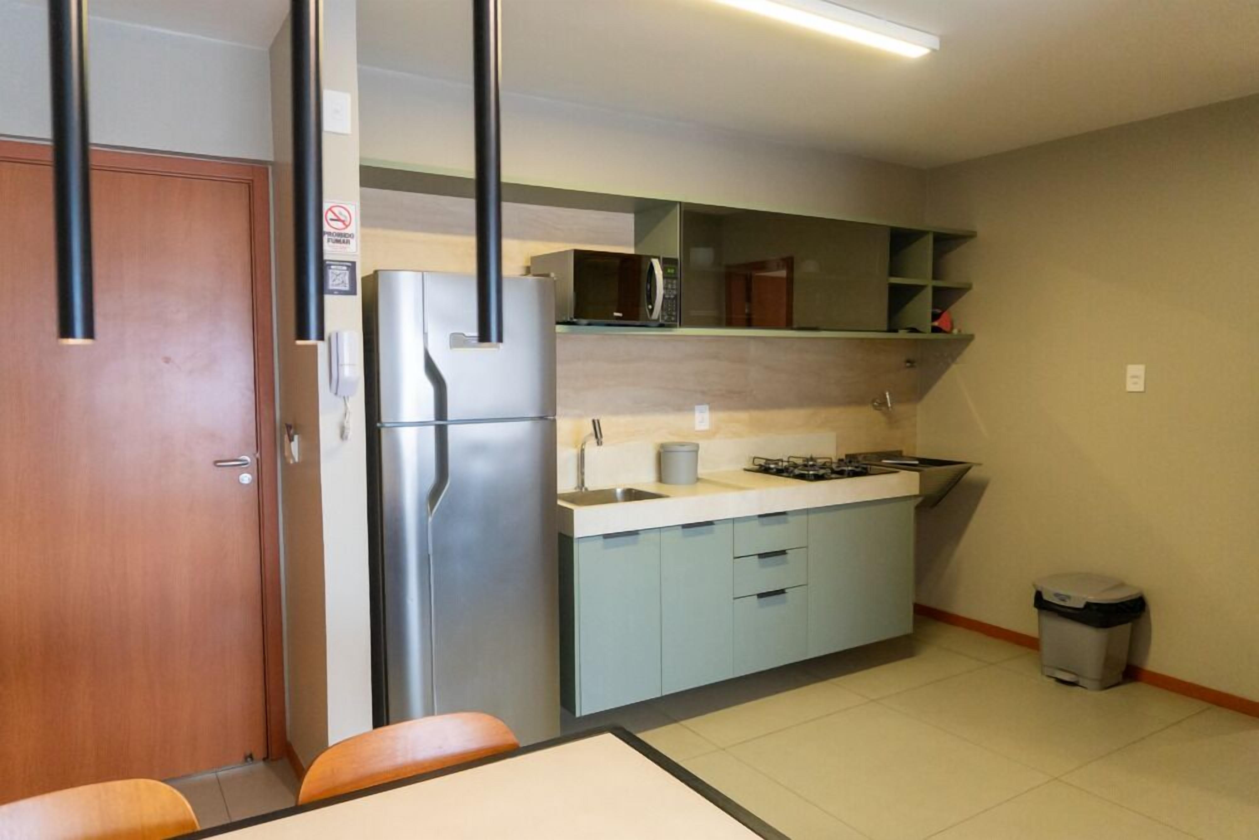 A compact kitchen with a refrigerator, microwave, sink, and stove.