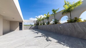 A modern building with a spacious terrace, palm trees, and a clear blue sky. - Top Unique Maceió  (Maceió)