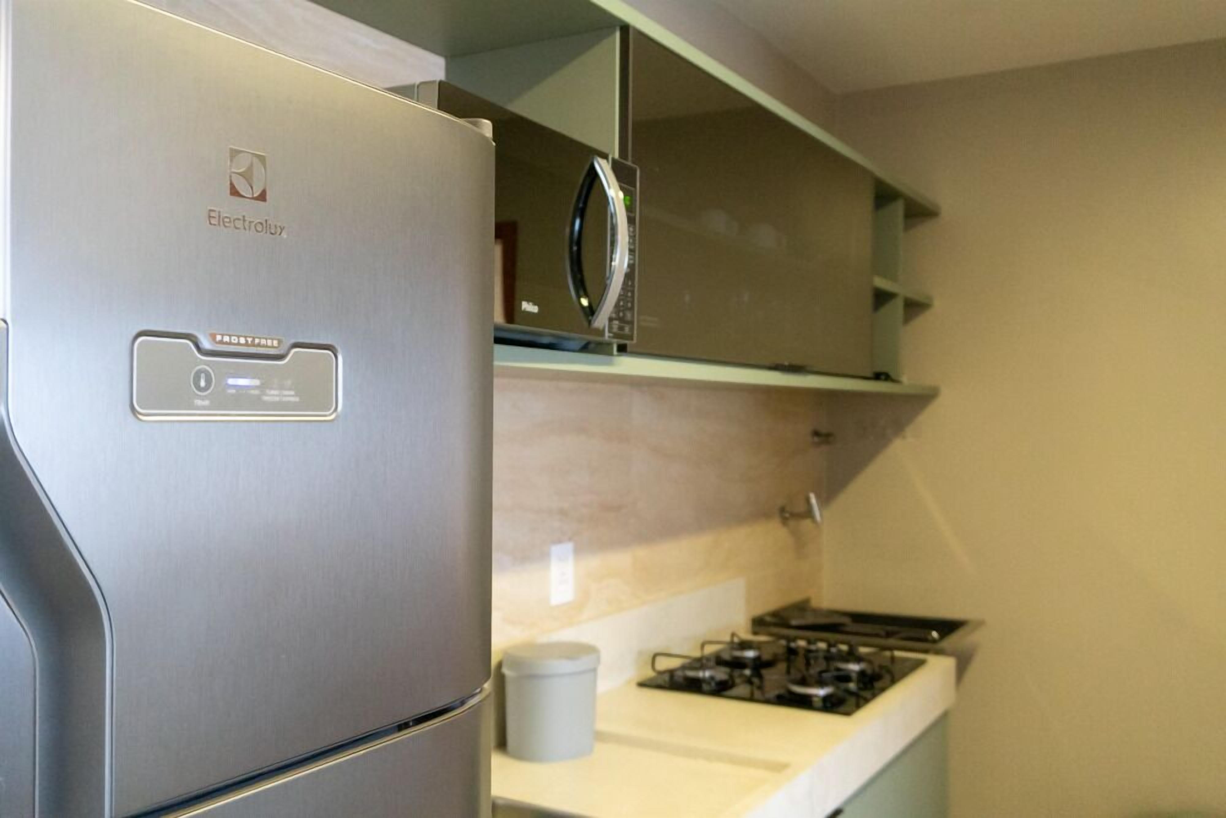 A stainless steel refrigerator with a 'FrostFree' label, a microwave above it, and a gas stove below.