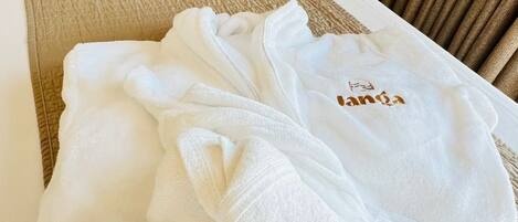A neatly made bed with a beige quilt and a white pillow.