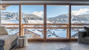 A spacious room with large windows offering a winter mountain view. - Outstanding 5 Bedroom Luxury Chalet, close to village centre, hot tub and sauna (Les Gets)