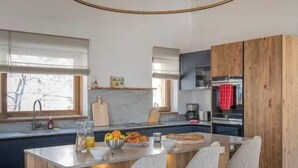 A modern kitchen with a central island, wooden cabinetry, and a view of the outdoors. - Outstanding 5 Bedroom Luxury Chalet, close to village centre, hot tub and sauna (Les Gets)