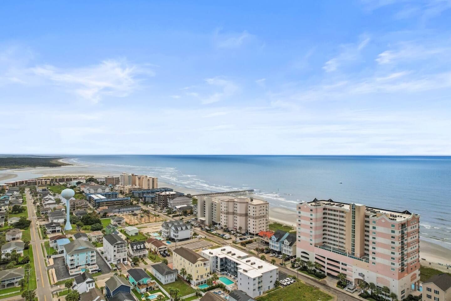 Een stadsgezicht aan de kust met een hotel aan het strand, woongebouwen en een helder uitzicht op de oceaan.