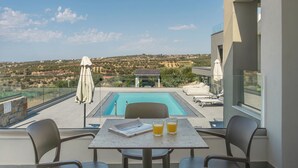 A balcony with a pool, outdoor seating, and a view of the countryside.