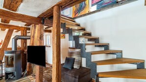 Un interior moderno con vigas de madera a la vista, una chimenea, un sofá y una escalera.