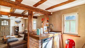 Una cocina rústica con vigas de madera a la vista, un respaldo de ladrillo y un extintor de incendios rojo.