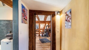 Un pasillo que conduce a un comedor con vigas de madera a la vista, una chimenea y vistas del espacio del comedor.